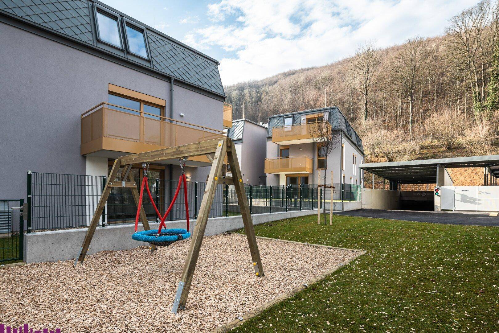 Wohnanlage mit Spielplatz, Schaukel und gepflegten Grünflächen für Familien.