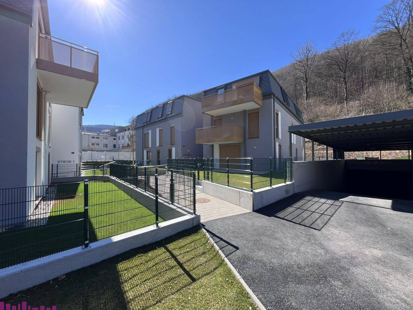 Moderne Wohnanlage mit Carport, gepflegten Grünflächen und Zugang zu den Gebäuden.