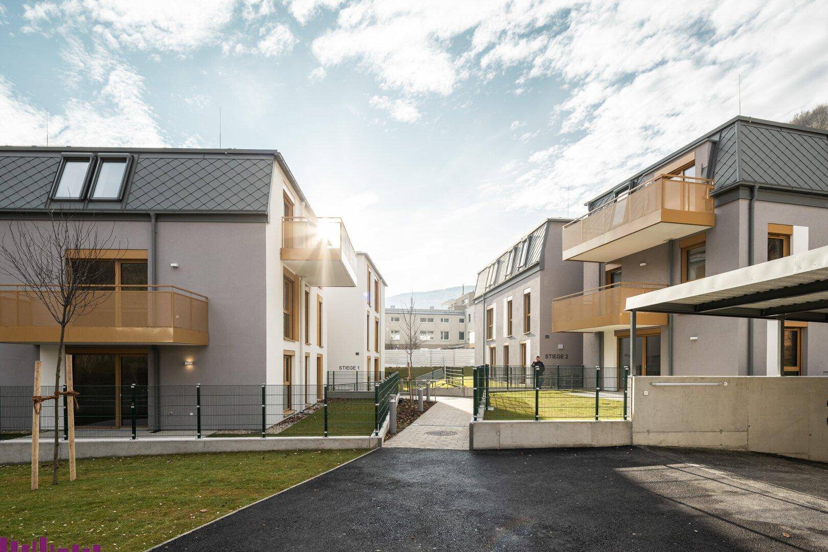 Moderne Wohnanlage mit zwei Gebäuden, gepflegten Außenbereichen und Zufahrt.