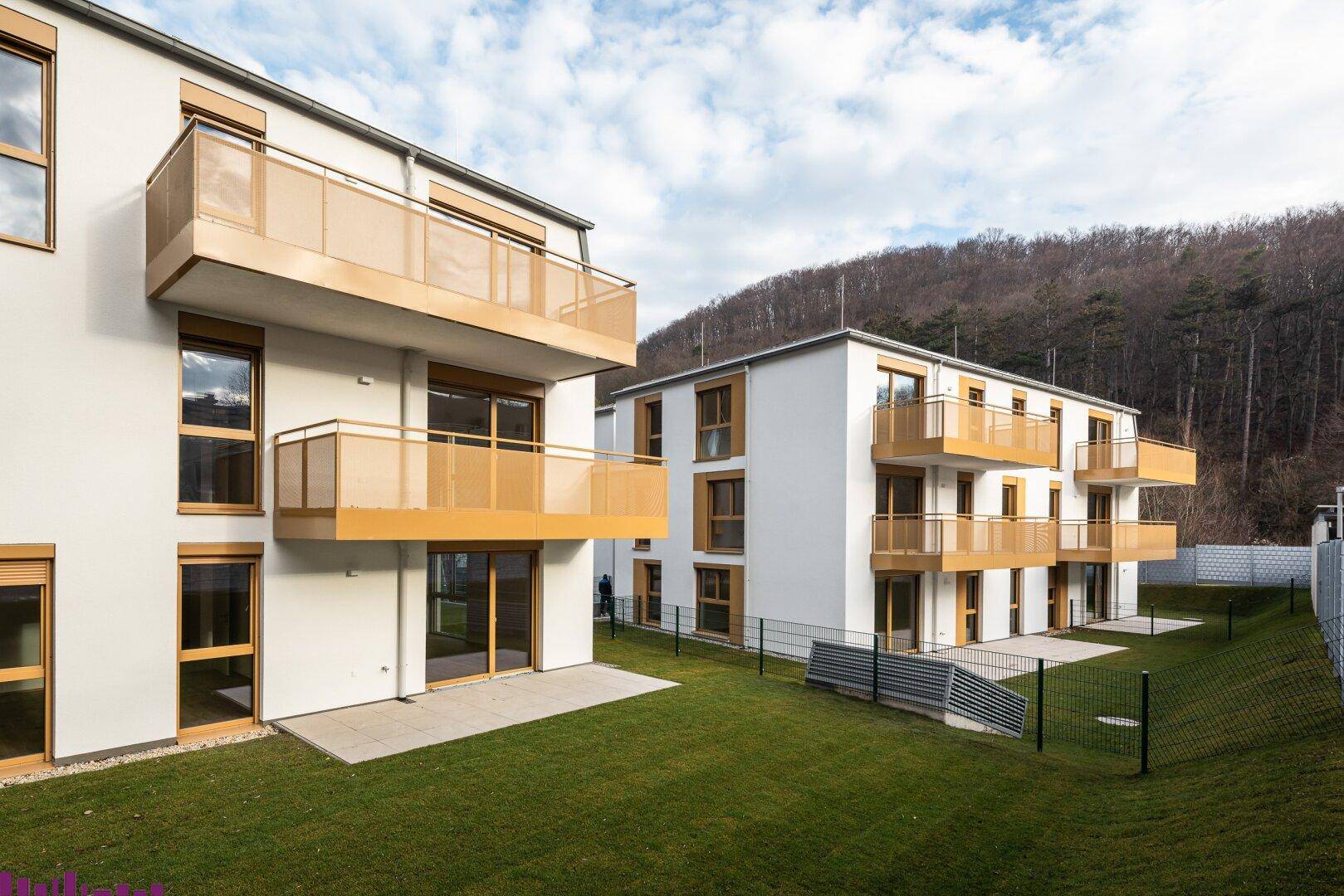 Moderne Wohngebäude mit Balkonen, Terrassen und weitläufigen Rasenflächen in sonniger Lage.