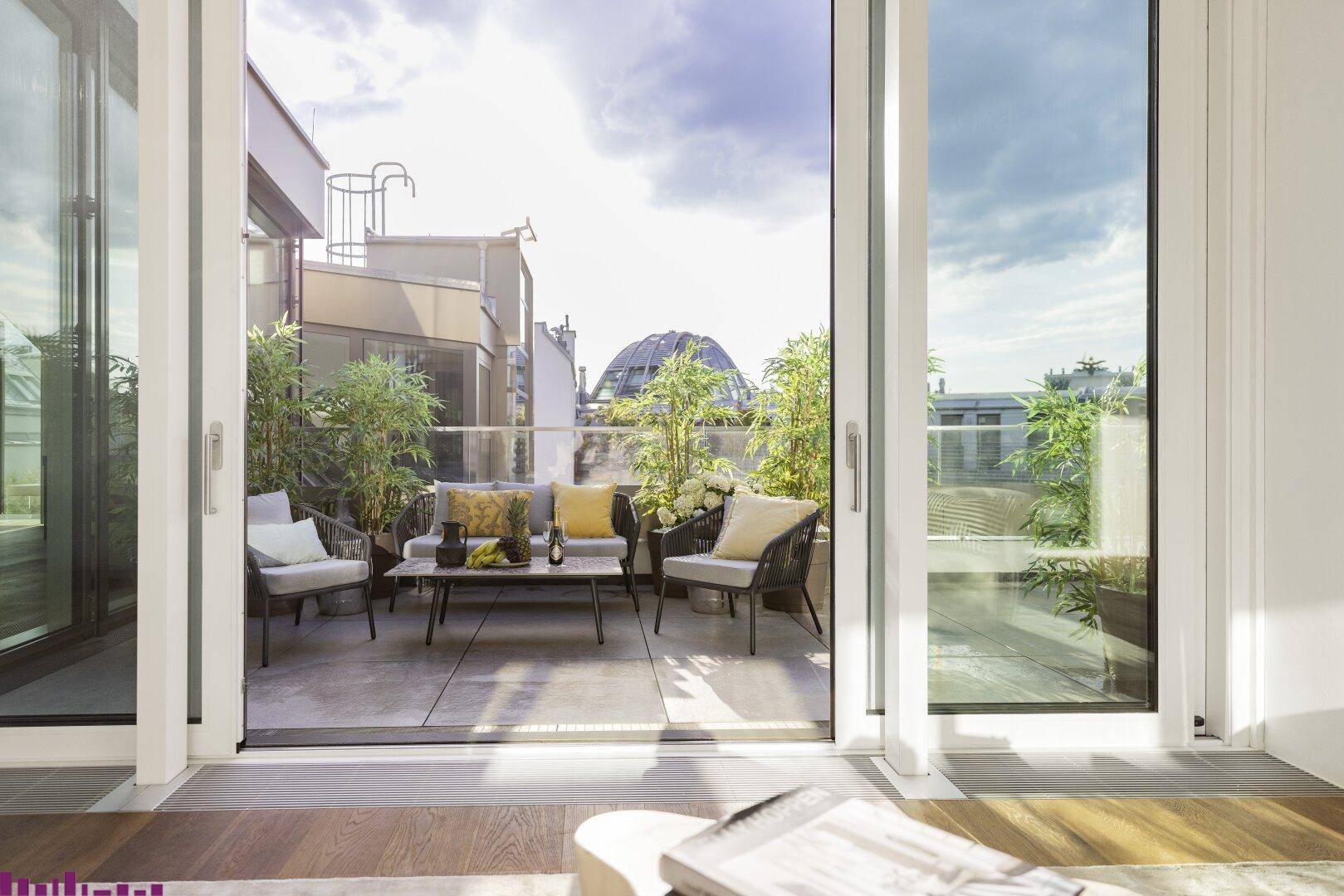 Gemütliche Terrasse mit Sitzgelegenheiten, Pflanzen und Blick auf die Stadt, zugänglich vom Wohnbereich.