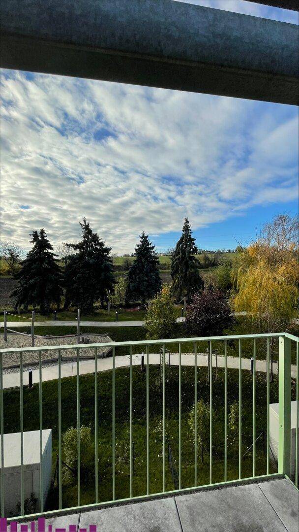 Blick vom Balkon auf eine grüne Landschaft mit Bäumen und sanften Hügeln.
