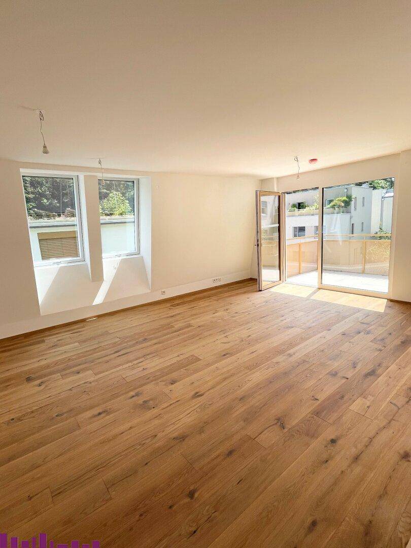 Helles Wohnzimmer mit Eichenparkett, großen Fenstern und Zugang zum Balkon, lichtdurchflutet.