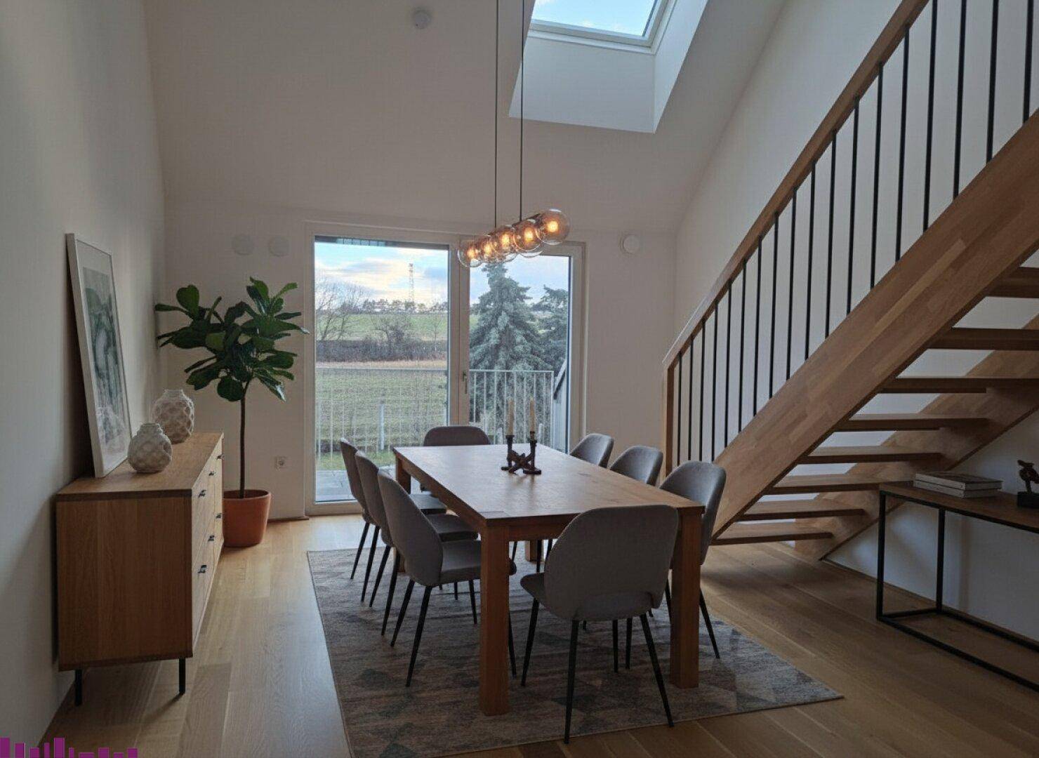 Heller Essbereich mit Holztisch, modernen Stühlen, Holztreppe und Zugang zum Außenbereich.