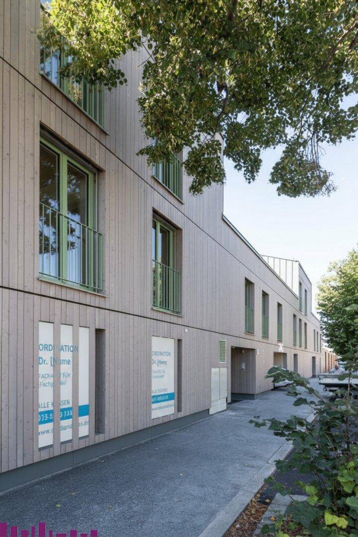 Moderne Holzfassade eines Mehrfamilienhauses mit Balkonen und großen Fenstern.