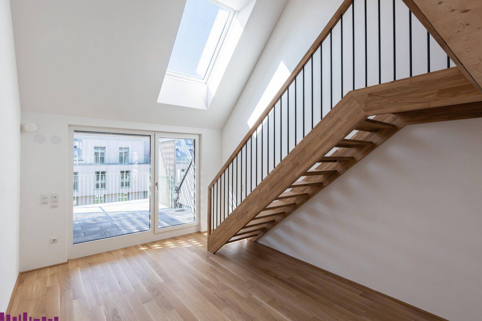 Heller Treppenbereich mit Holzboden und Zugang zu einer Terrasse durch große Glasschiebetüren.