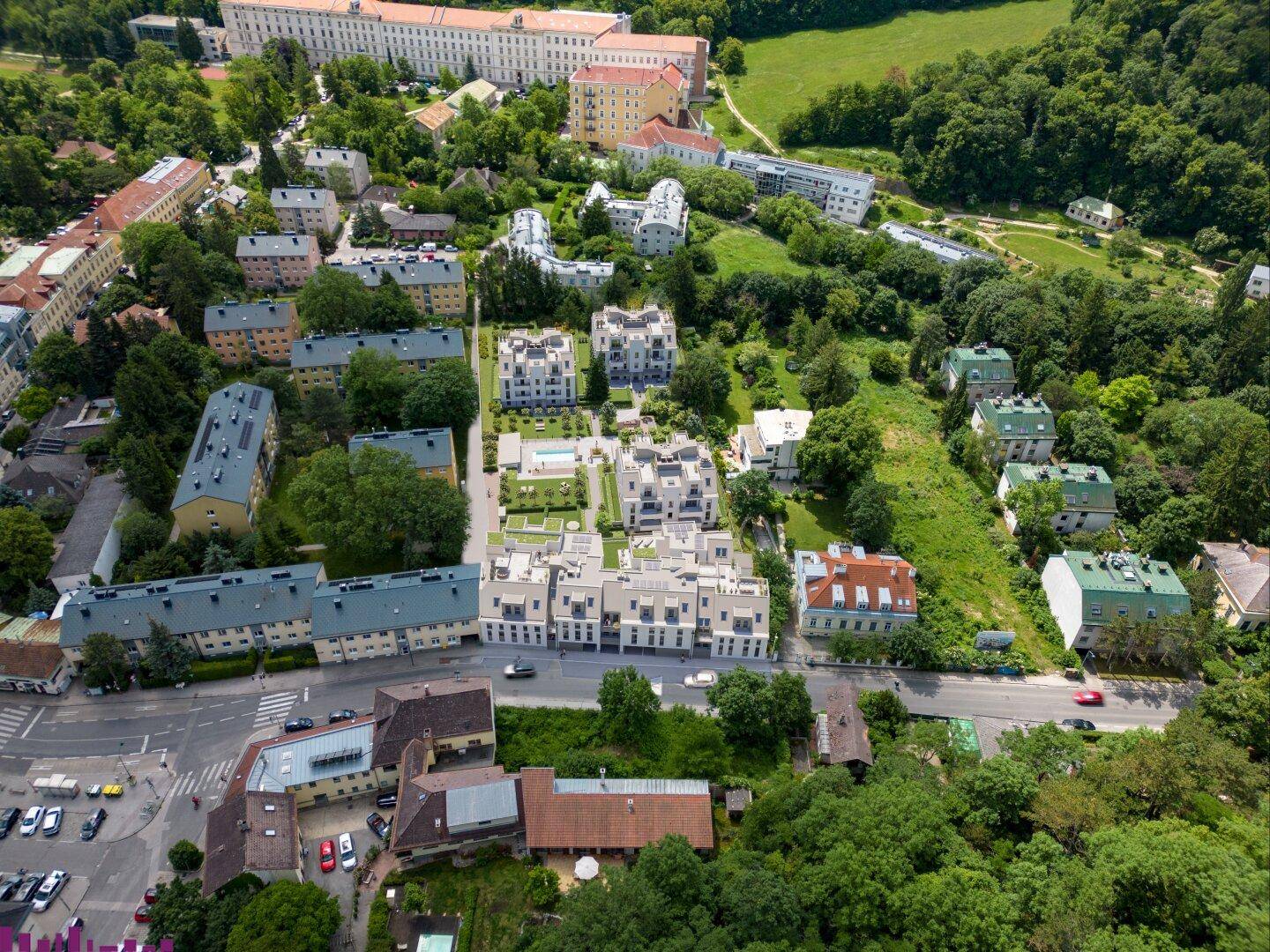 Luftaufnahme einer Wohngegend mit neuen Gebäuden, umgeben von viel Grün und älteren Bauten.