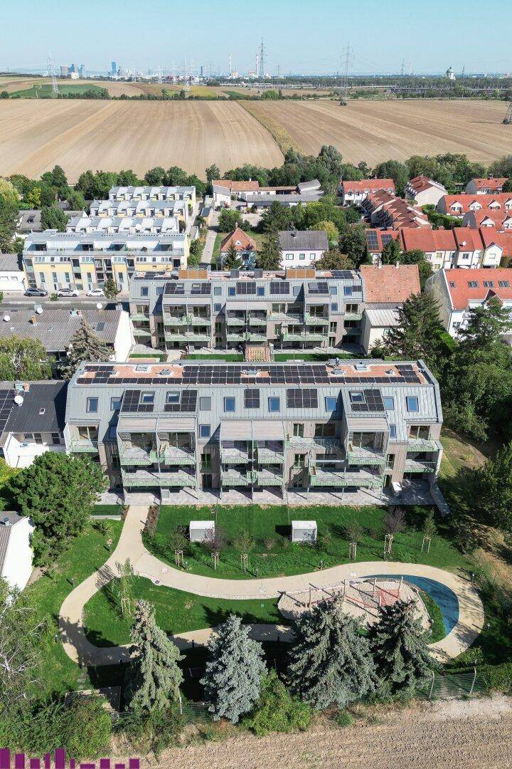 Luftaufnahme einer modernen Wohnsiedlung mit Solaranlagen, Spielplatz und weitem Blick ins Grüne.