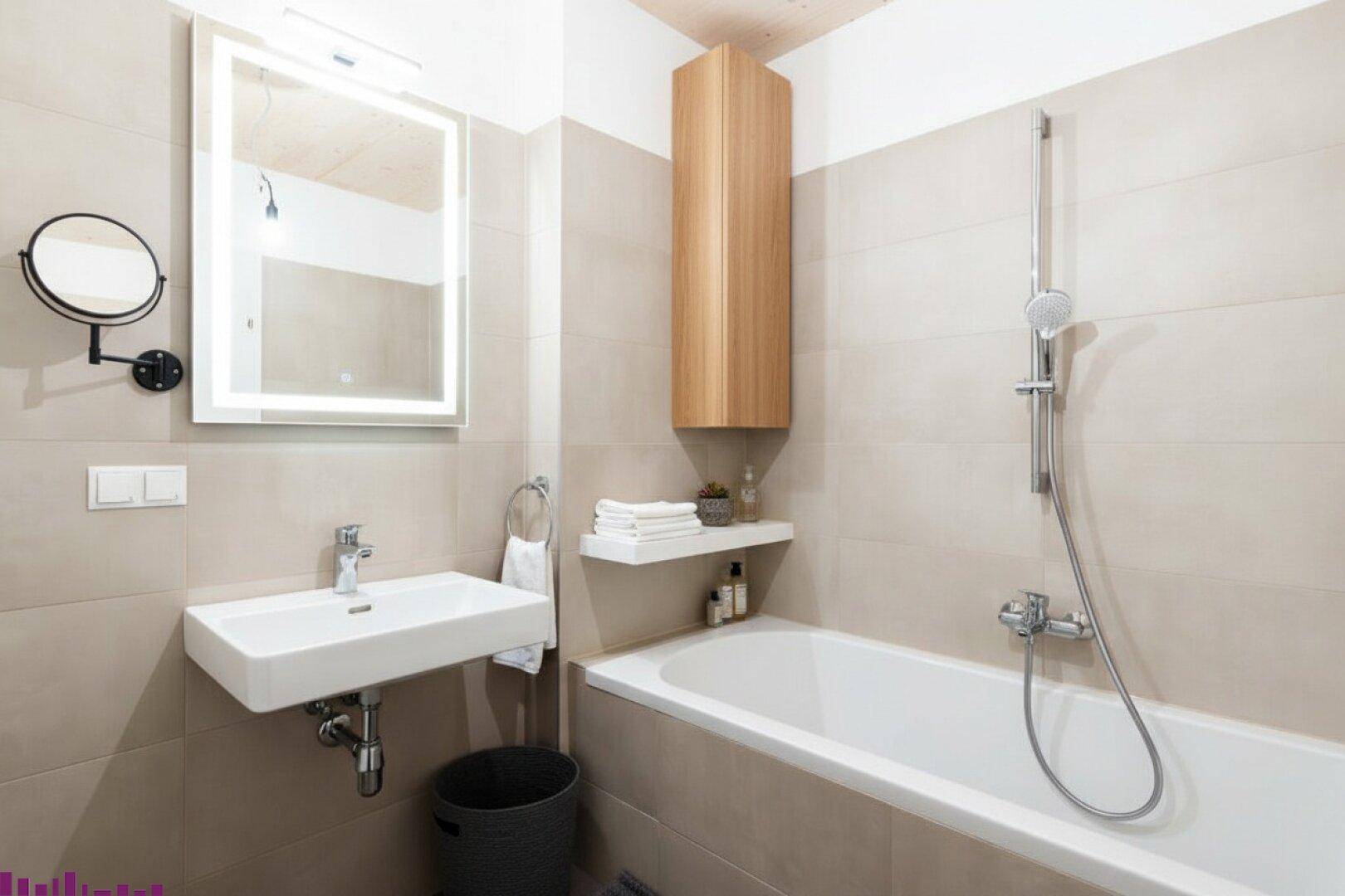 Modernes Badezimmer mit Badewanne, Duscharmatur, Waschbecken und beleuchtetem Spiegelschrank.