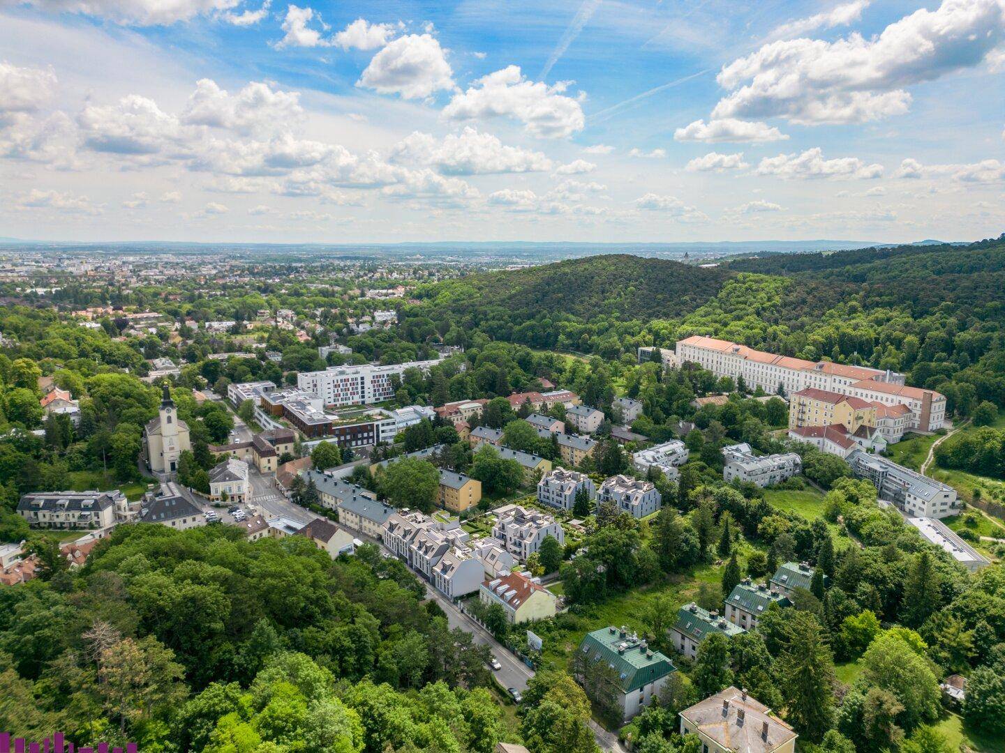 Weitläufige Luftaufnahme der Stadt und der grünen Umgebung mit der Wohnanlage.