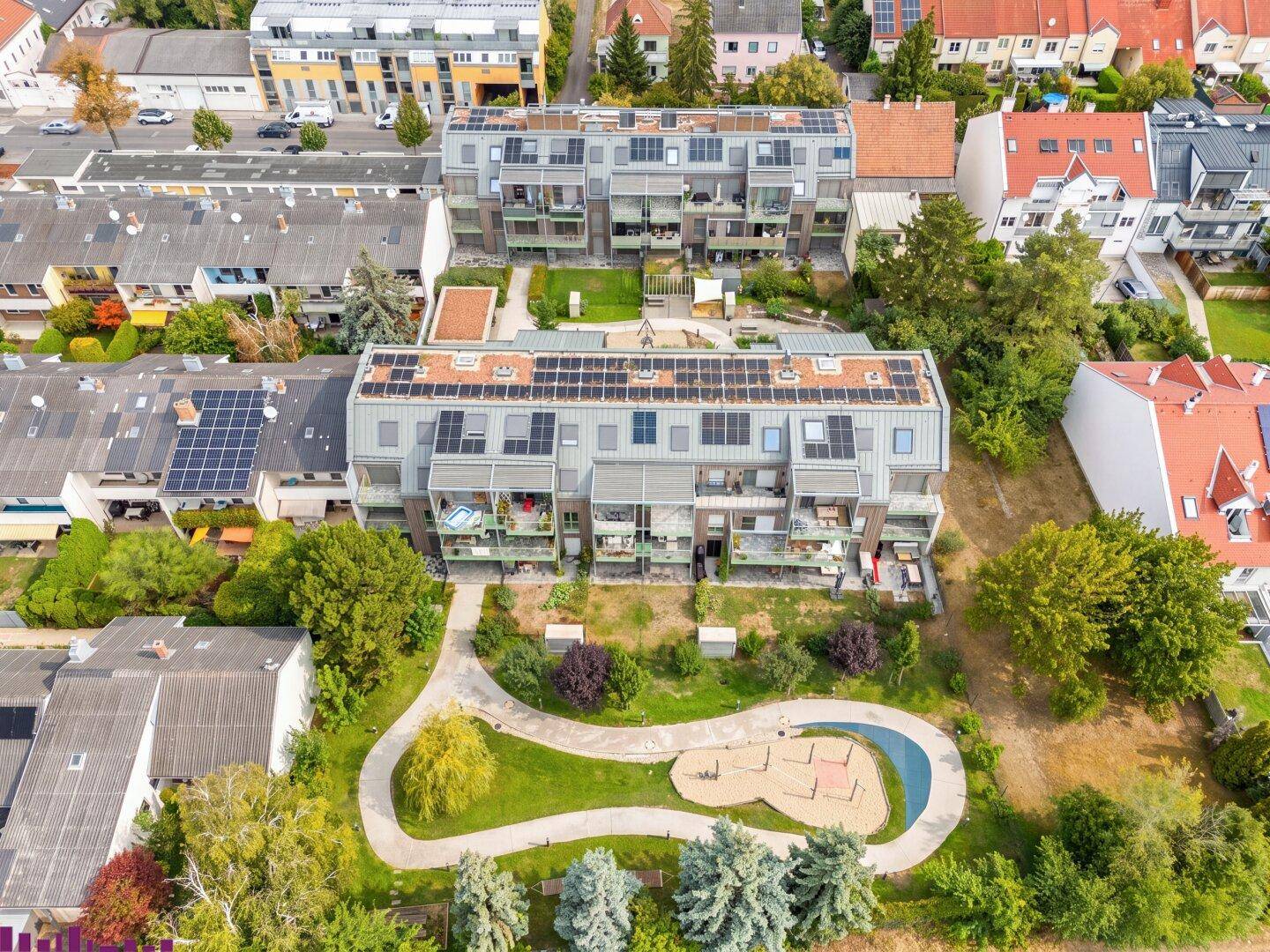 Luftaufnahme einer modernen Wohnanlage mit Solarpaneelen und großzügigen Grünflächen inklusive Spielplatz.