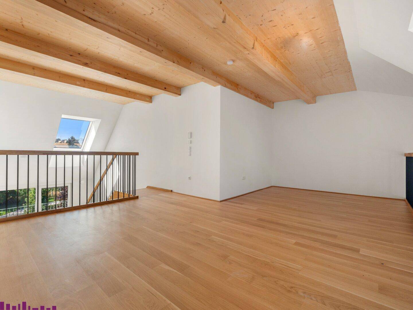 Geräumiger Dachbodenraum mit sichtbaren Holzbalken, Holzboden und Dachfenster, bietet viel natürliches Licht.