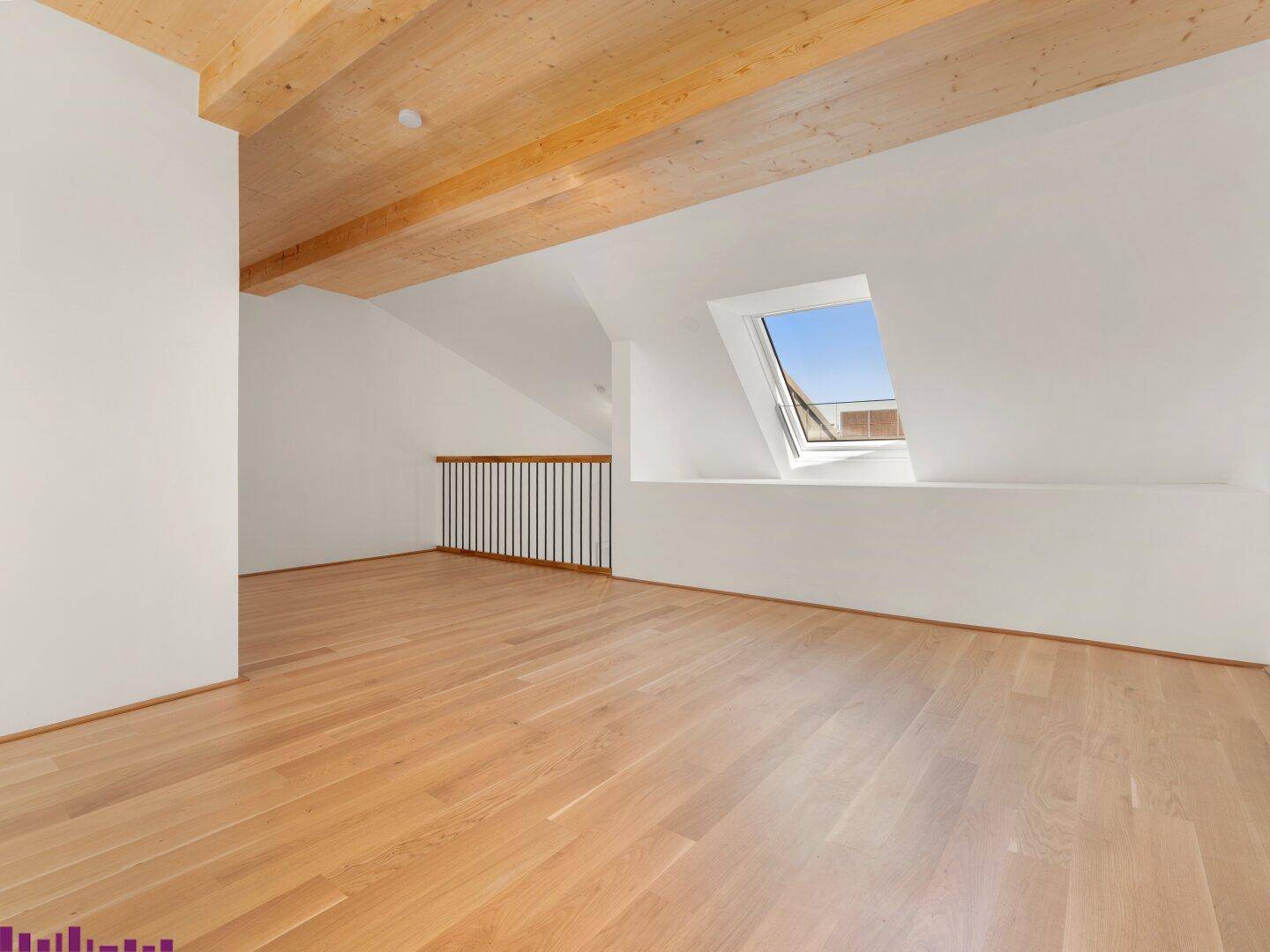 Lichtdurchfluteter Dachbodenbereich mit Holzbalken und Parkettboden, bietet eine offene und luftige Atmosphäre.