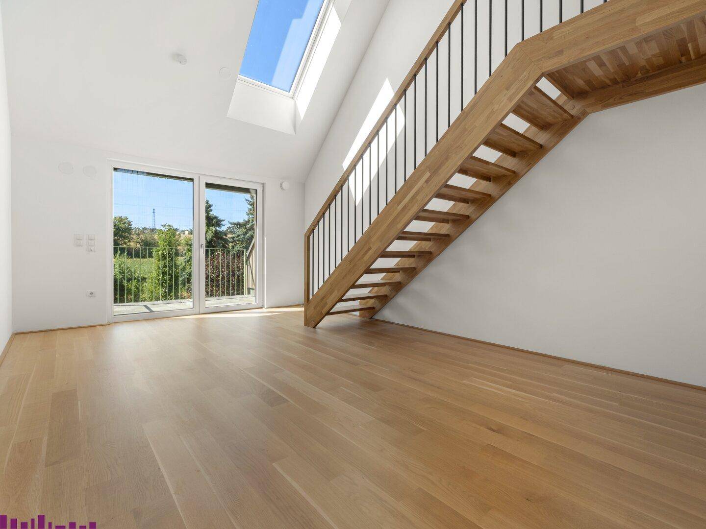 Heller Wohnbereich mit Holztreppe, Parkettboden und Zugang zu einem Balkon mit Weitblick.