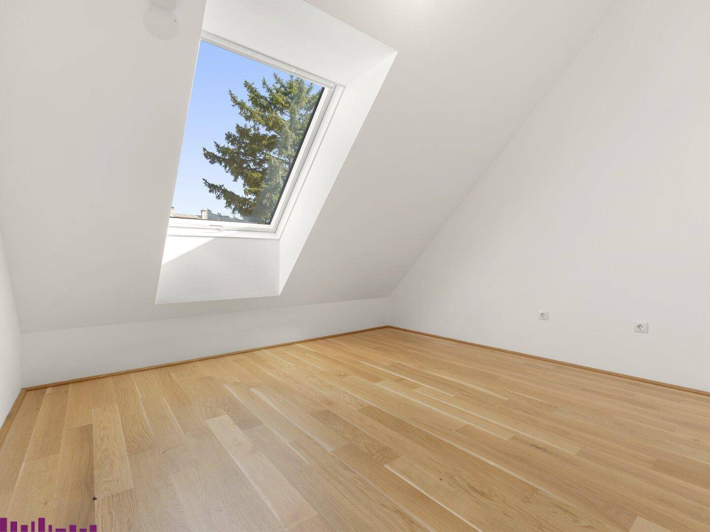 Helles Schlafzimmer im Dachgeschoss mit Holzboden und großem Dachfenster, bietet viel Tageslicht.