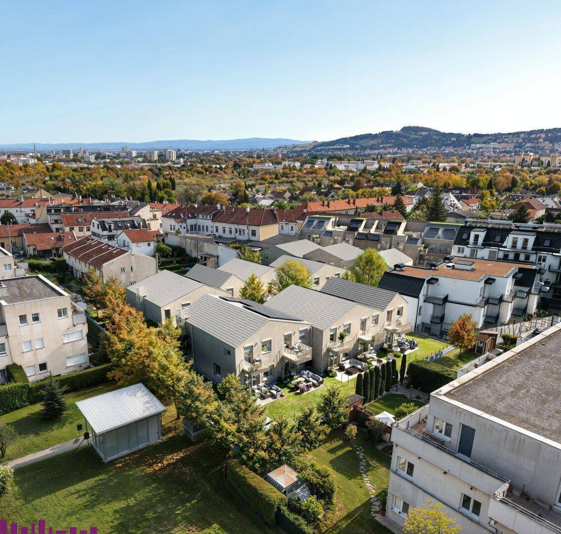 Luftaufnahme einer modernen Wohnsiedlung mit Gärten und Balkonen in städtischer Umgebung.