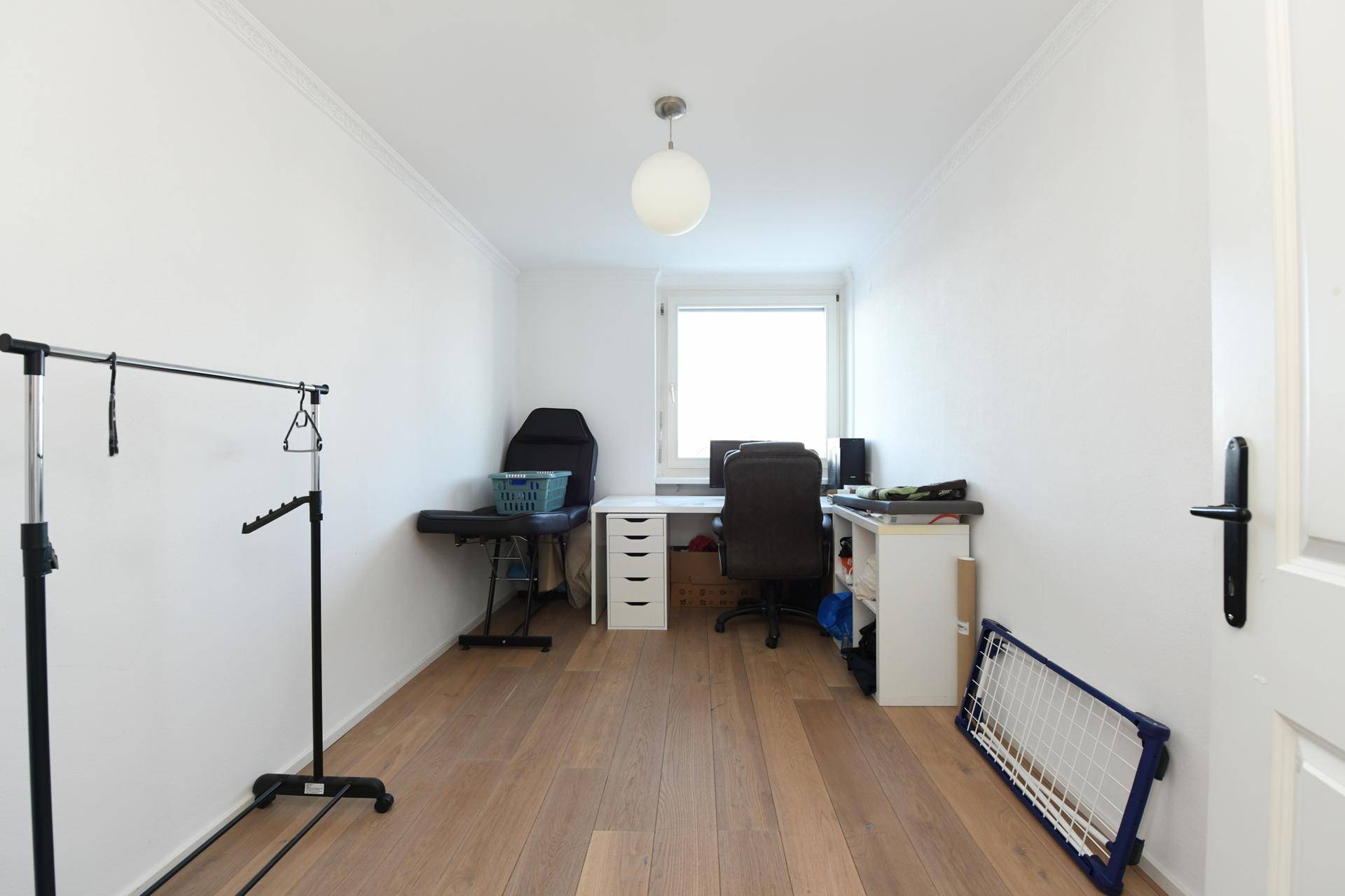 Helles Zimmer mit Holzboden, Schreibtisch und Fenster, ideal als Büro.