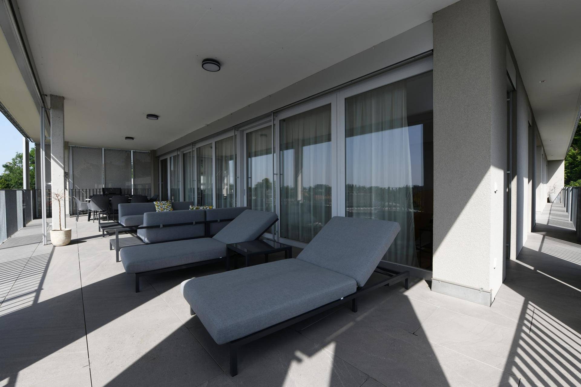 Geräumige Terrasse mit modernen Liegestühlen und weitem Blick über die Stadt.