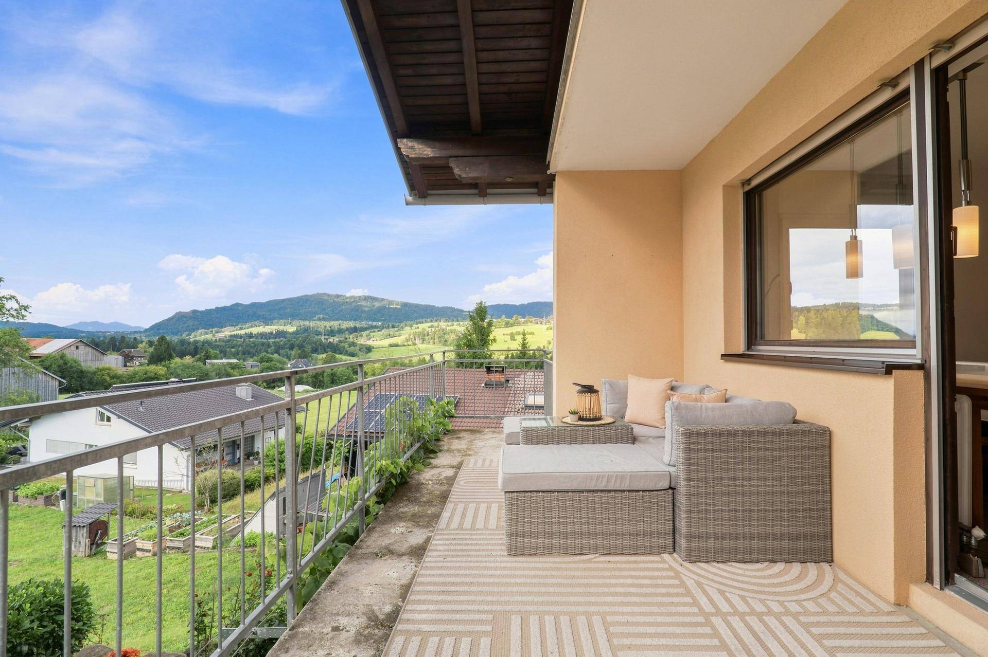 Möblierter Balkon mit gemütlicher Sitzecke und weitem Panoramablick auf die grüne Hügellandschaft.