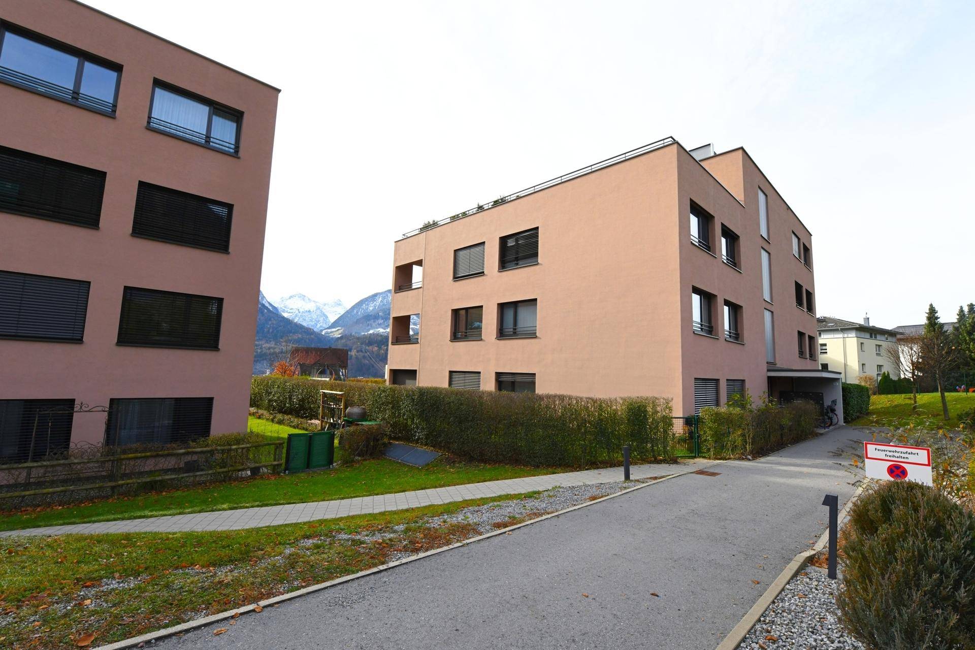Zwei moderne Wohngebäude mit gepflegten Grünflächen und Zufahrtsweg.