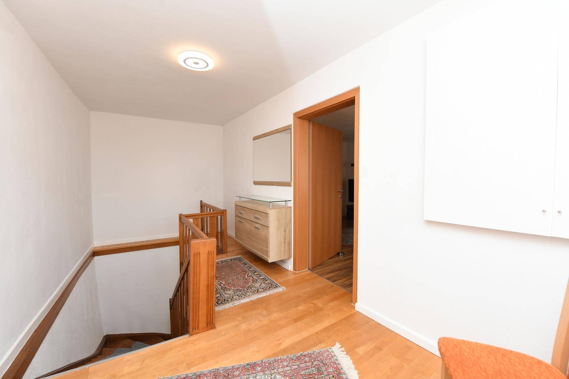 Heller Flur mit Holztreppe und Garderobenbereich, der zum Obergeschoss führt.