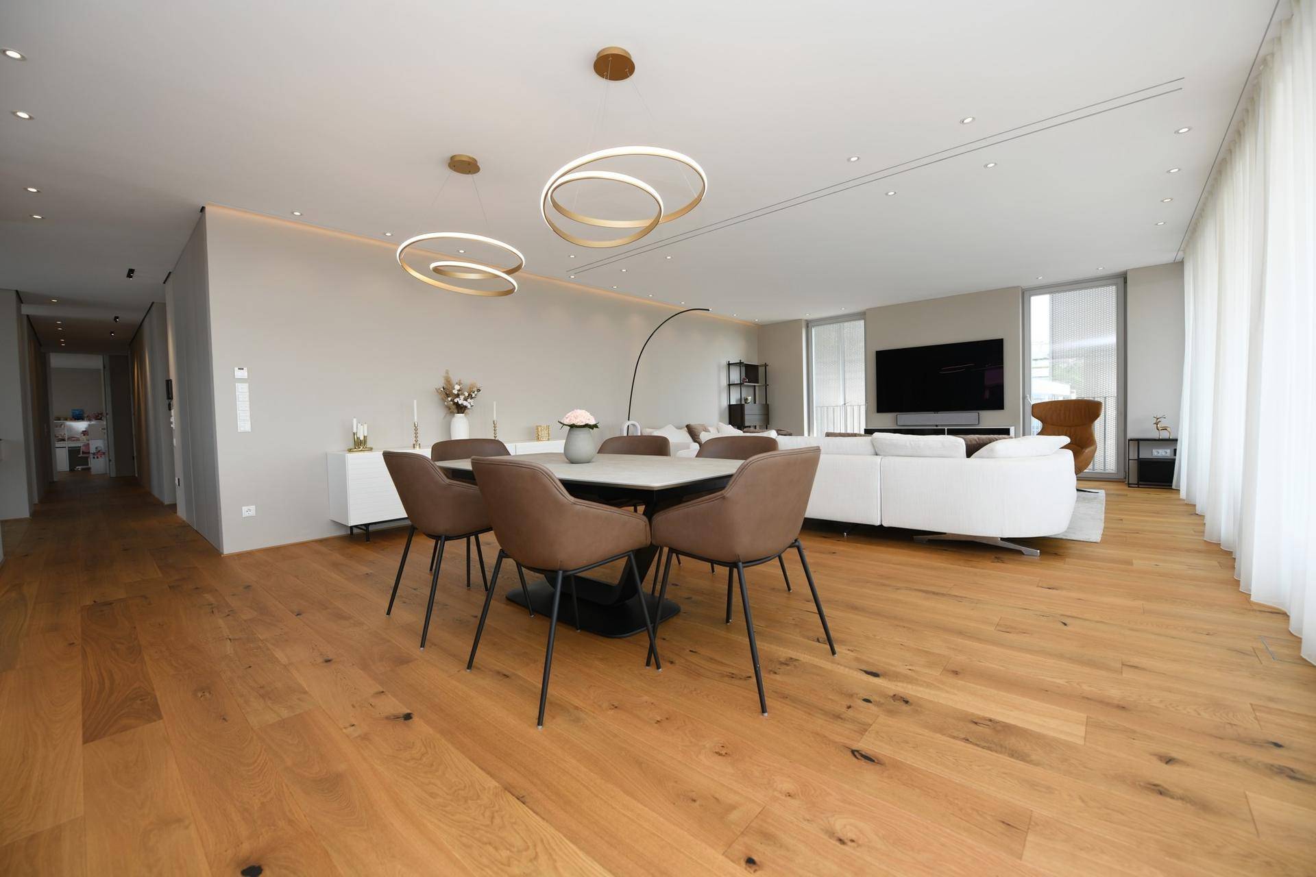 Heller Essbereich mit Holzboden und modernem Esstisch, offen zum Wohnzimmer.
