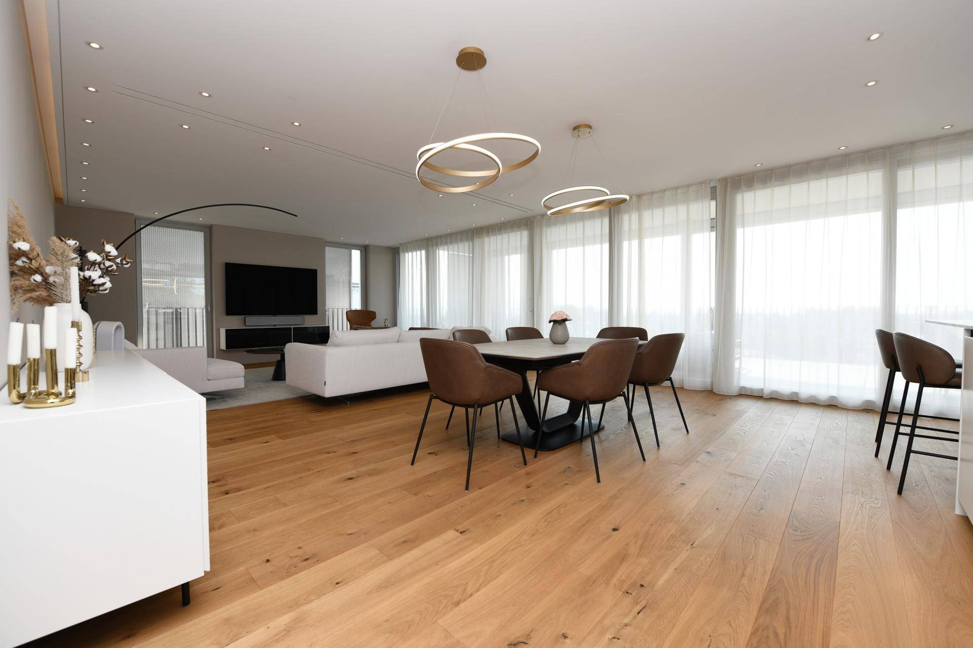 Moderner Essbereich mit Holzboden, elegantem Esstisch und Blick auf den Wohnbereich.