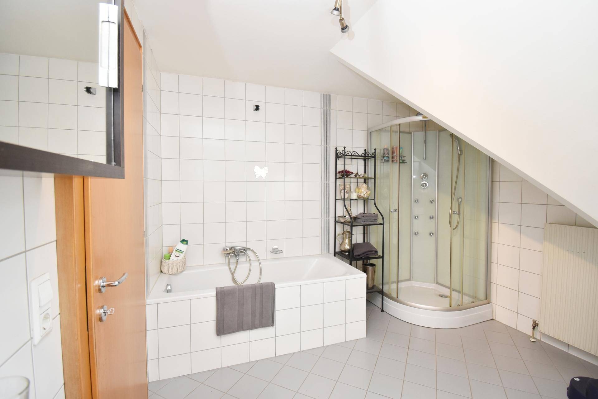 Badezimmer mit Badewanne, Duschkabine und Dachschräge.