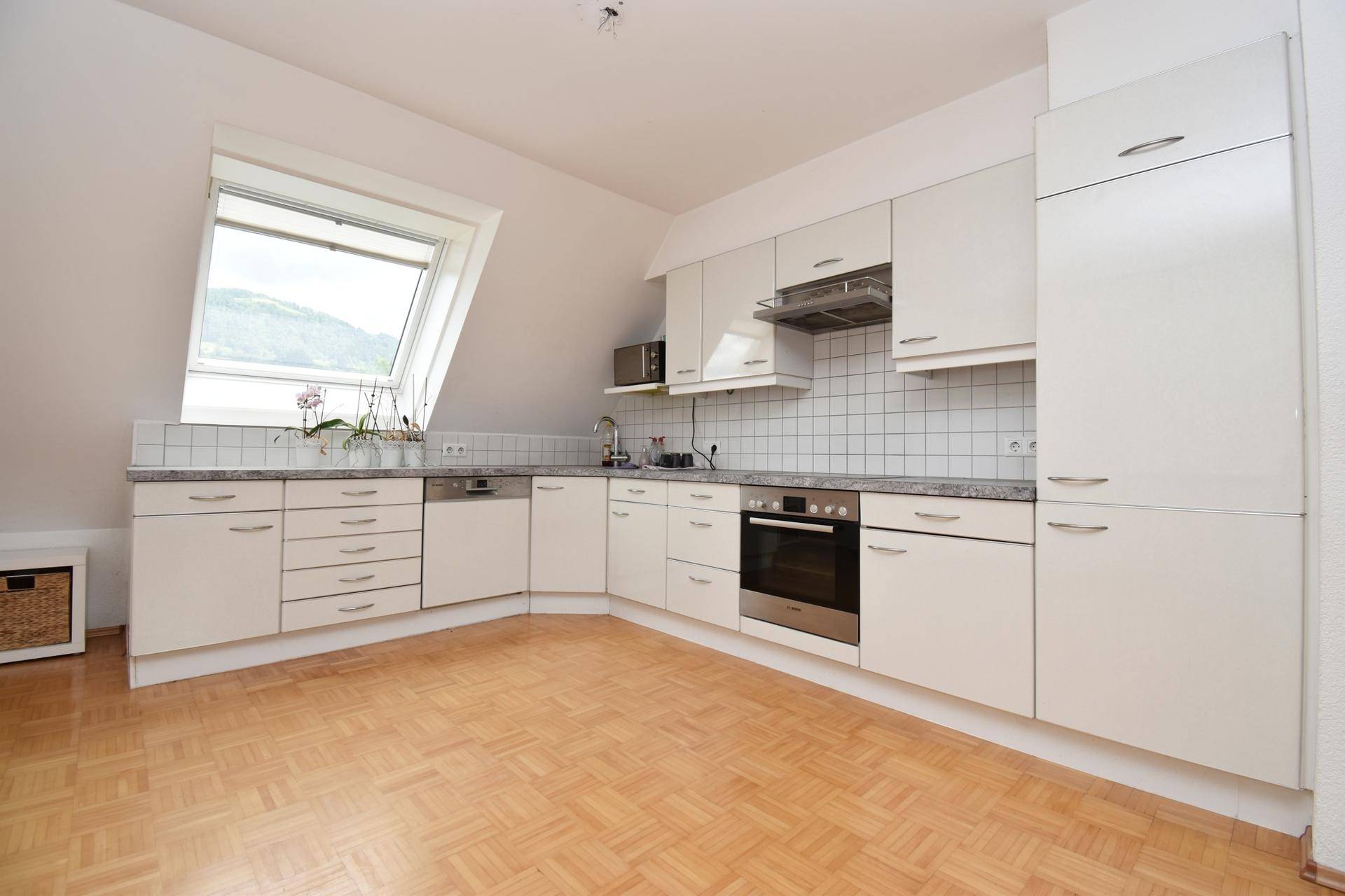 Helle Einbauküche mit Dachfenster, modernen Geräten und viel Arbeitsfläche.