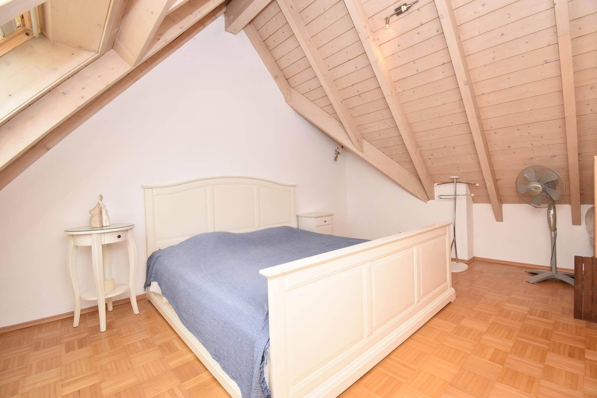 Schlafzimmer mit Holzdachschräge, Parkettboden und klassischem Bett.