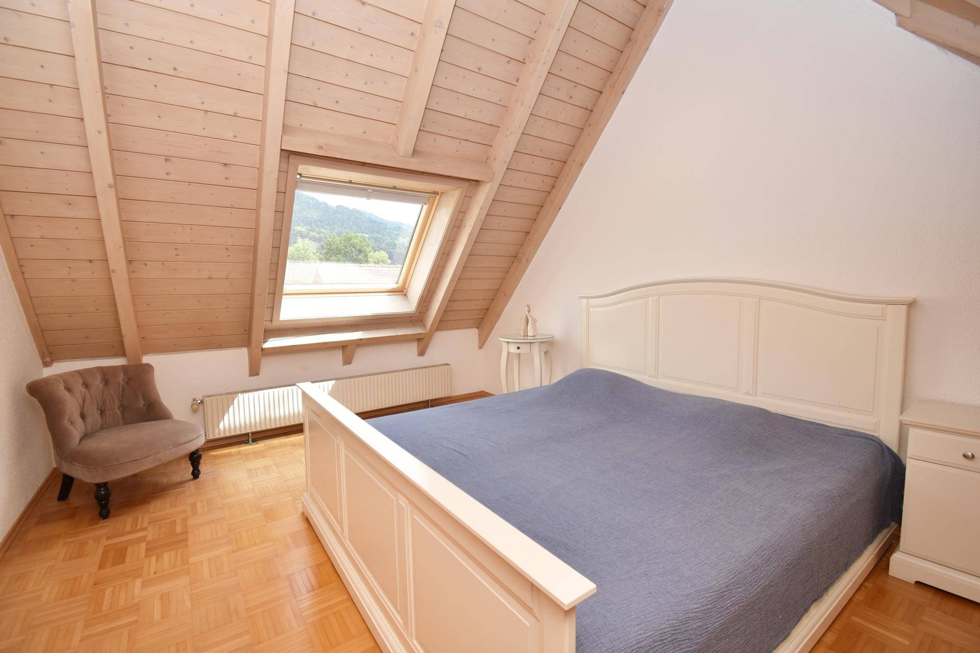 Gemütliches Schlafzimmer mit Doppelbett, Dachfenster und Holzdachschräge.