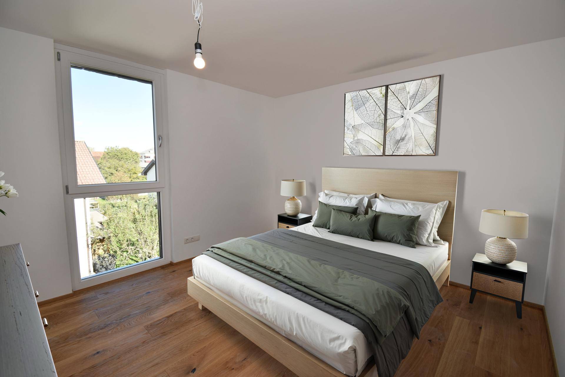 Gemütliches Schlafzimmer mit Holzboden, großem Fenster und modernem Bett, hell und einladend.