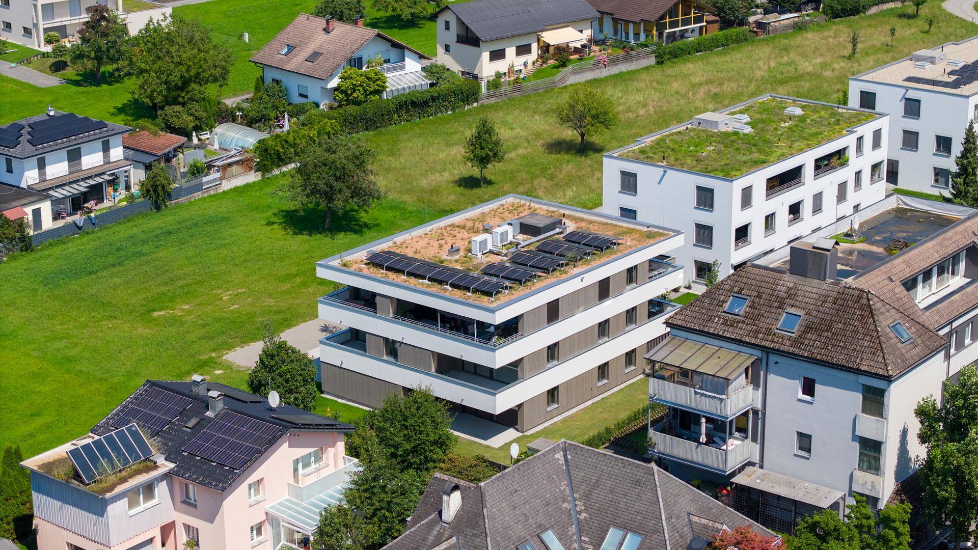 Luftaufnahme eines modernen Wohngebäudes mit Gründach und Solaranlage in ländlicher Umgebung.
