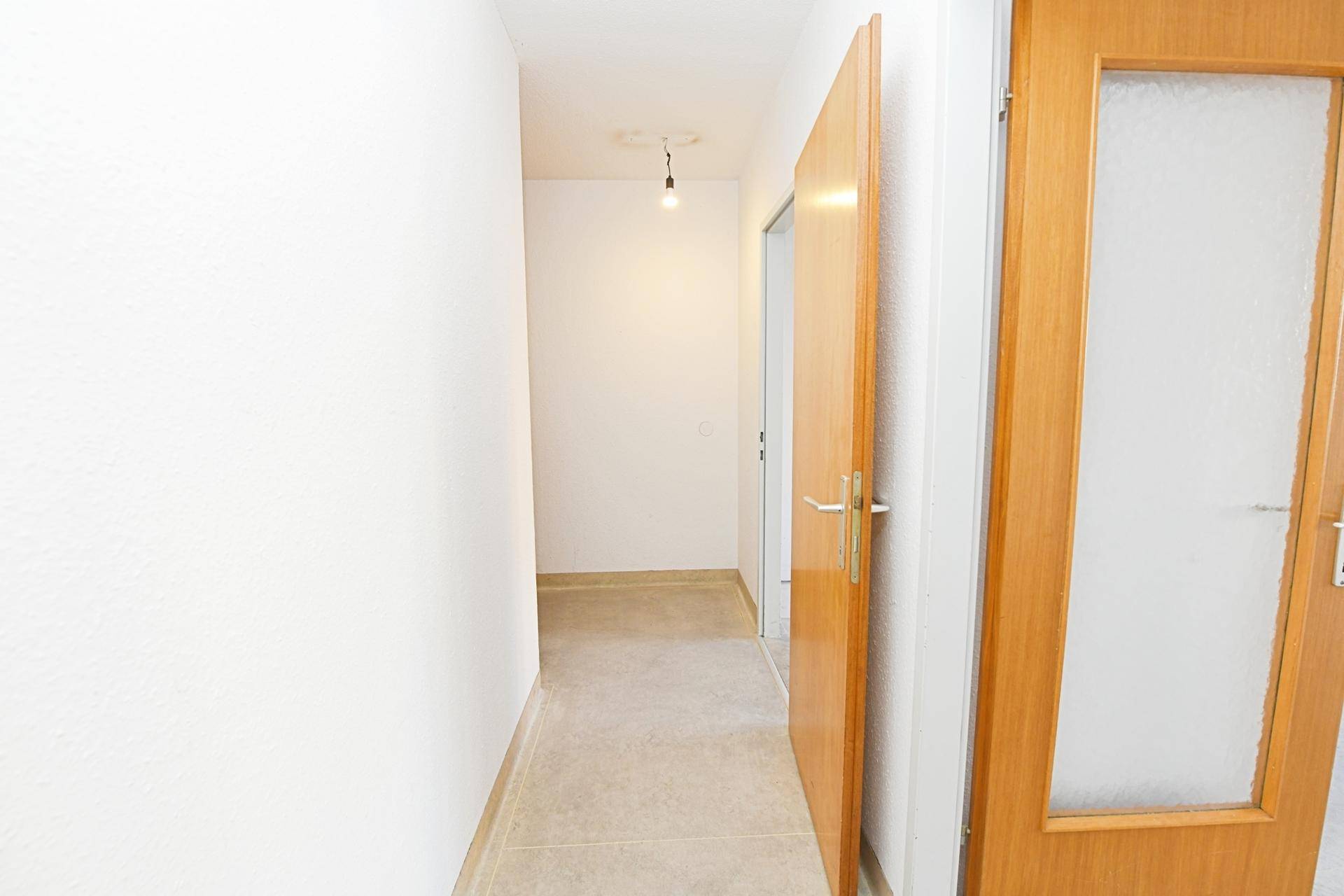 Heller Flur mit Fliesenboden und Holztüren, verbindet die verschiedenen Wohnbereiche.