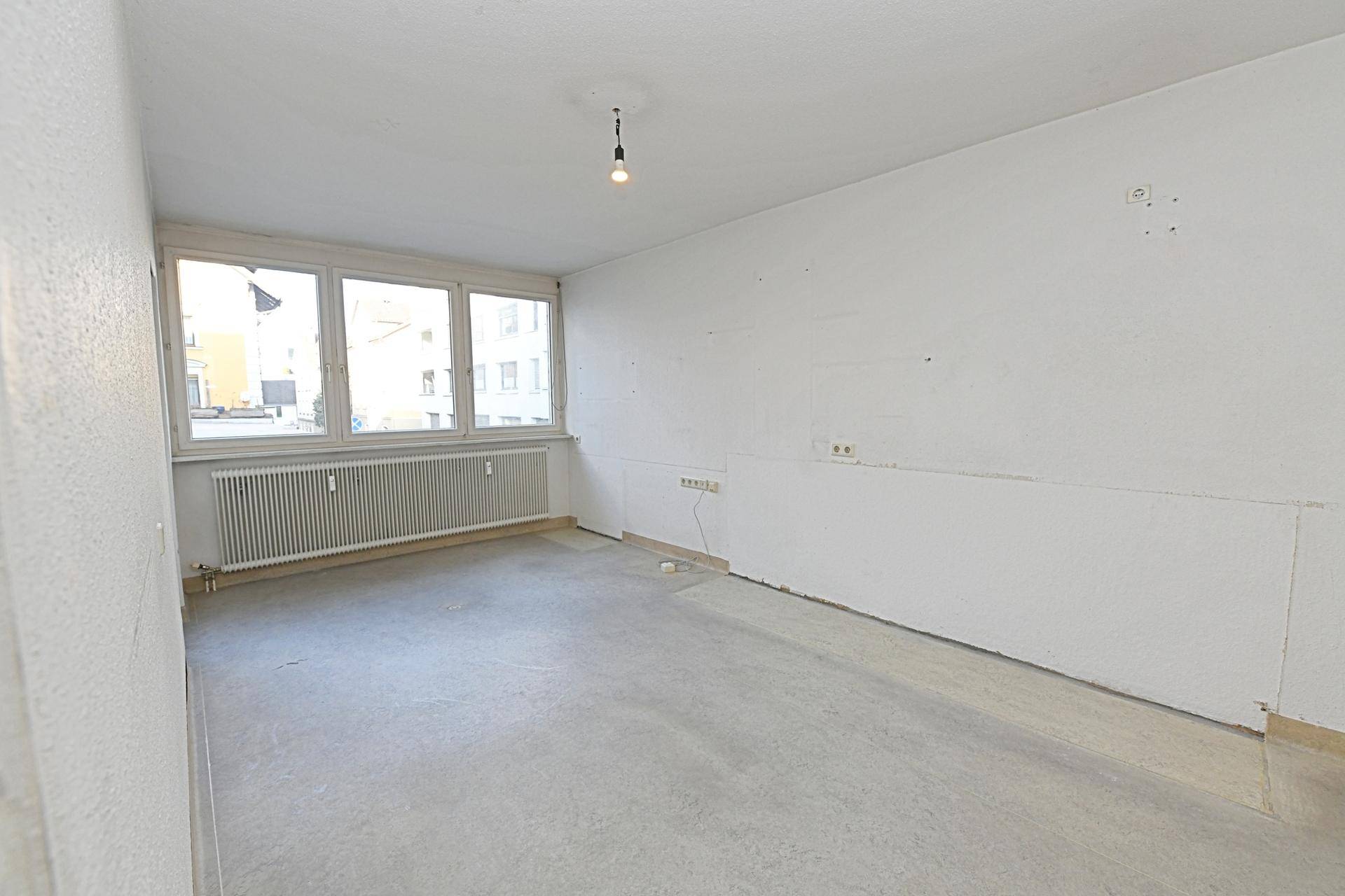 Heller, leerer Raum mit großen Fenstern und Betonboden, ideal für individuelle Einrichtung.