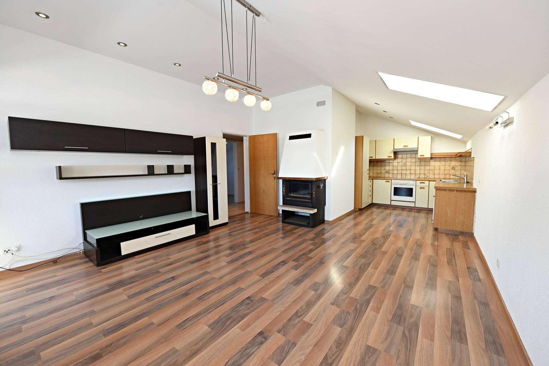 Heller Wohn- und Küchenbereich mit Laminatboden, Kamin und Dachfenstern für viel Licht.