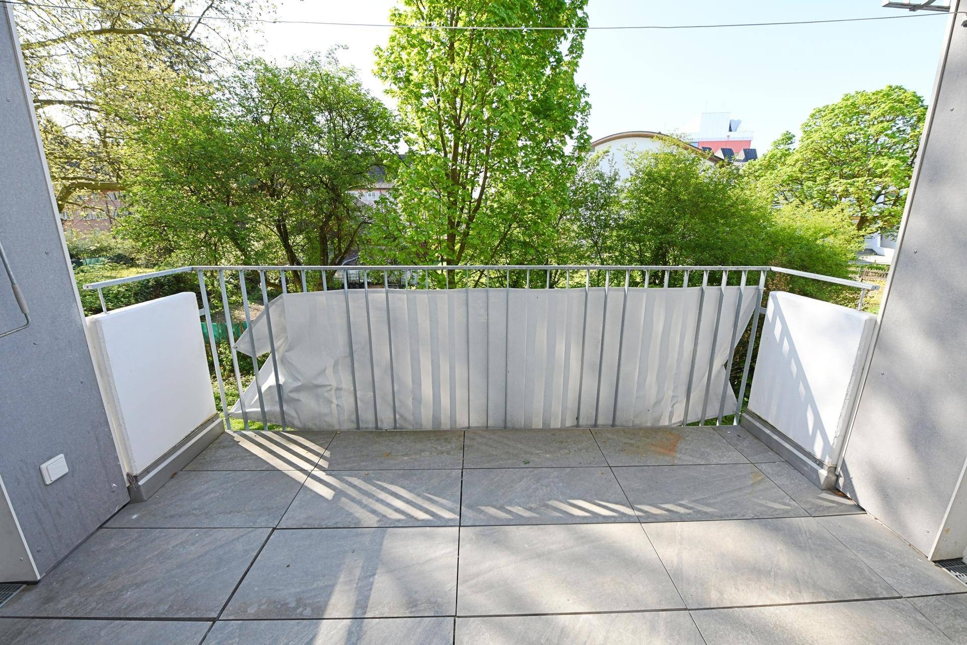 Heller Balkon mit Fliesenboden und Metallgeländer, ideal zum Entspannen im Freien.
