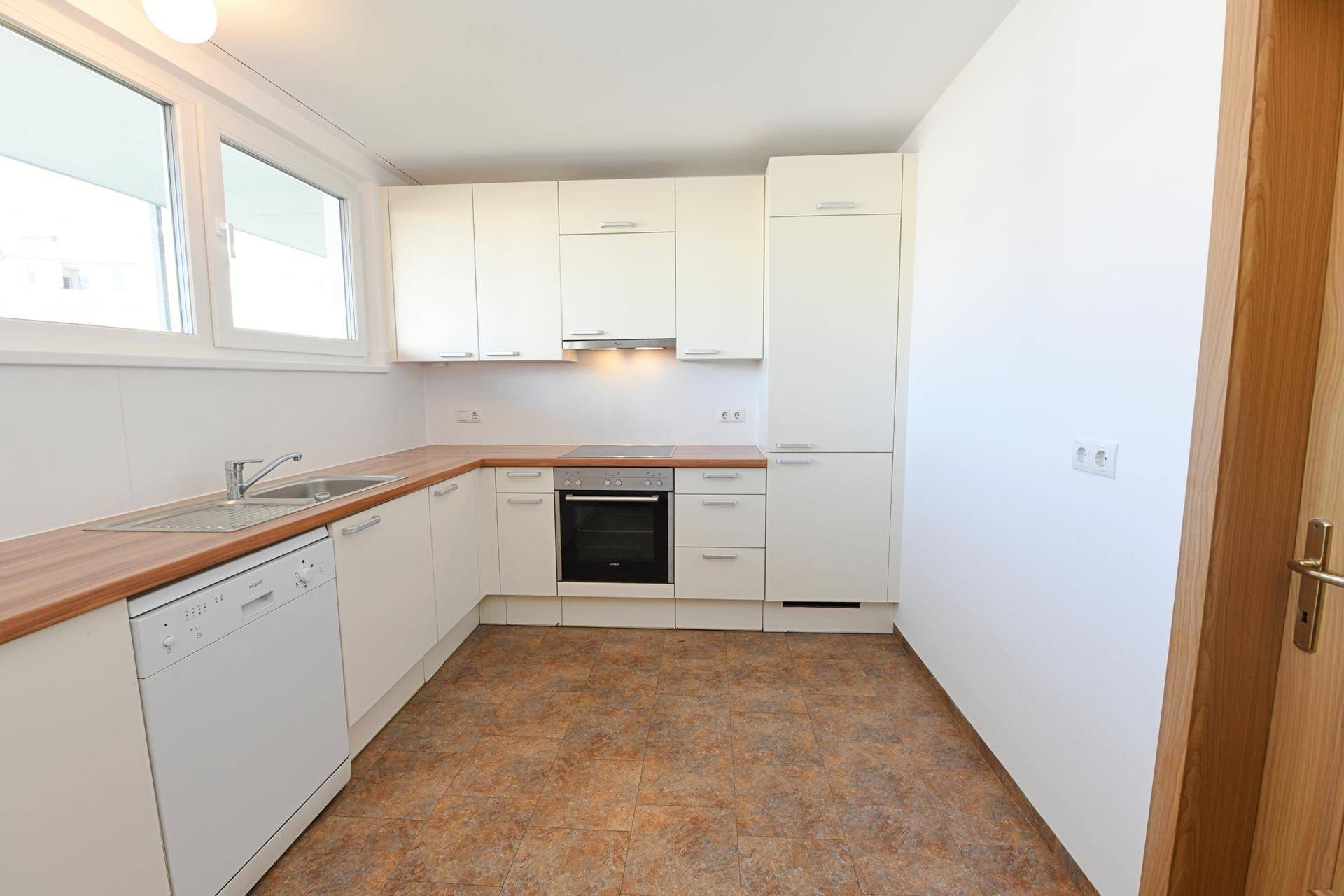 Helle Einbauküche mit weißen Fronten, Holz-Arbeitsplatte und modernen Geräten, praktisch und sauber.
