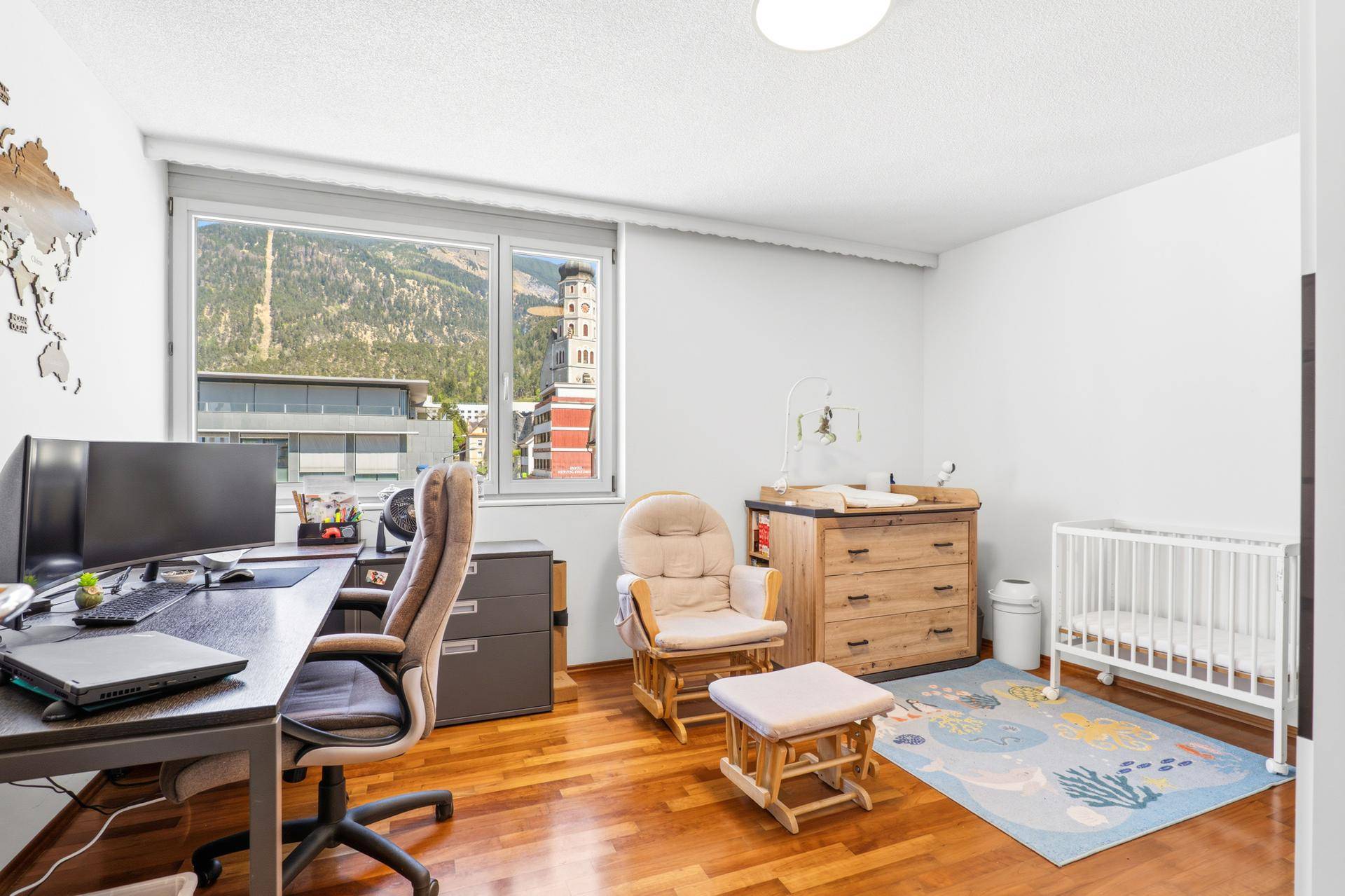 Vielseitiges Zimmer, genutzt als Büro und Kinderzimmer, mit Holzboden und Fensterblick.