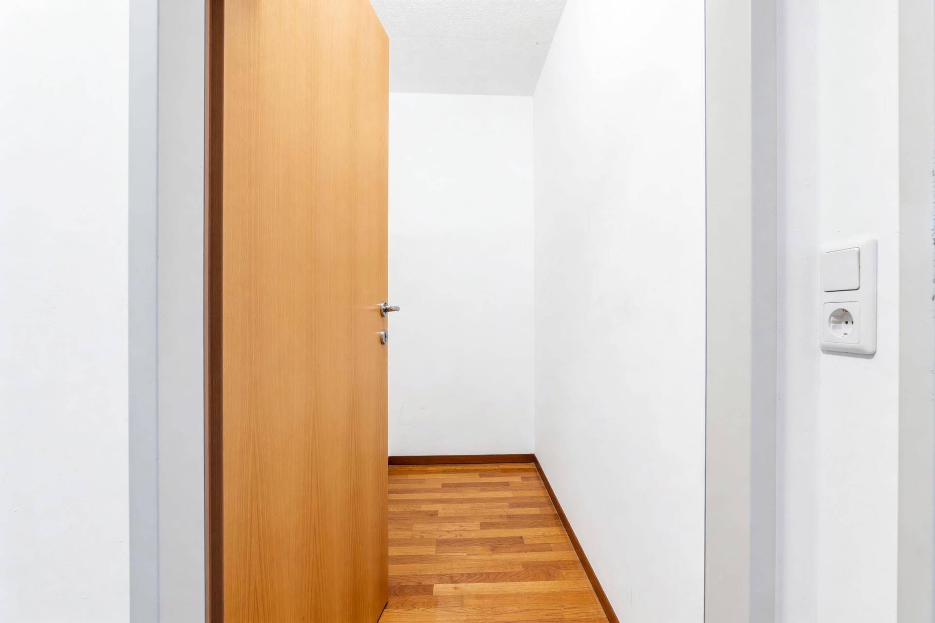Heller Flur mit Holzboden und weiß gestrichenen Wänden, schlicht und funktional.