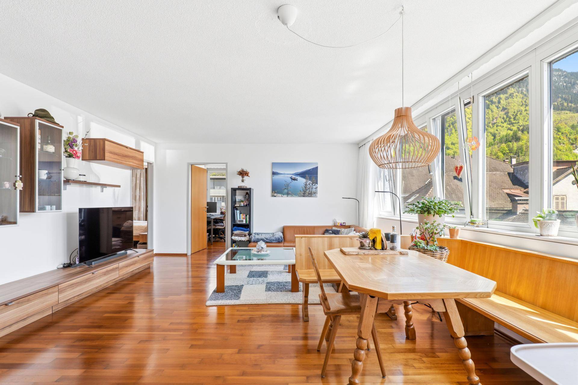 Geräumiger Wohn-Essbereich mit Holzboden, viel Tageslicht und traditionellen Holzmöbeln.