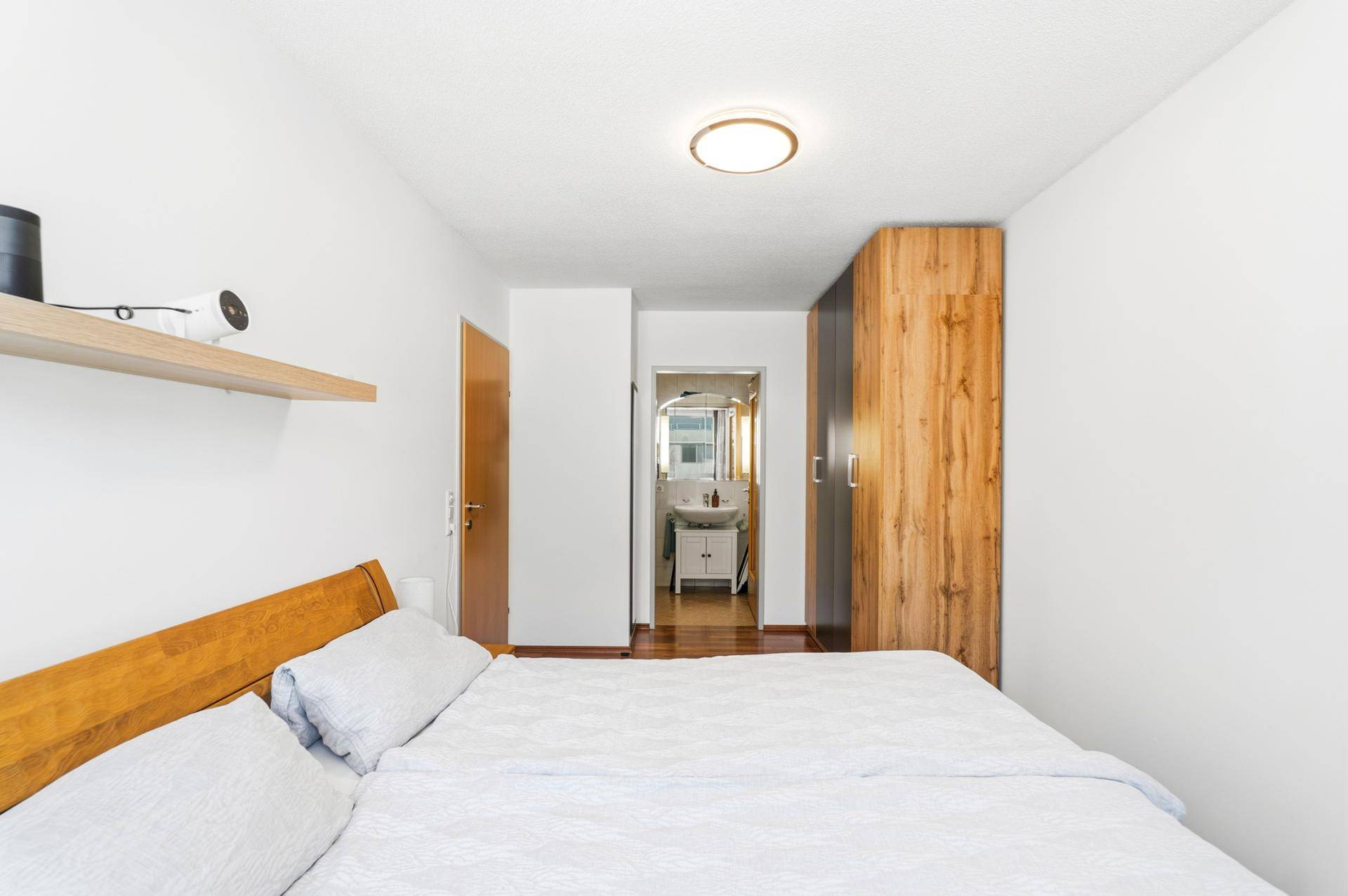 Schlafzimmer mit Holzboden und direktem Zugang zu einem angrenzenden Badezimmer.