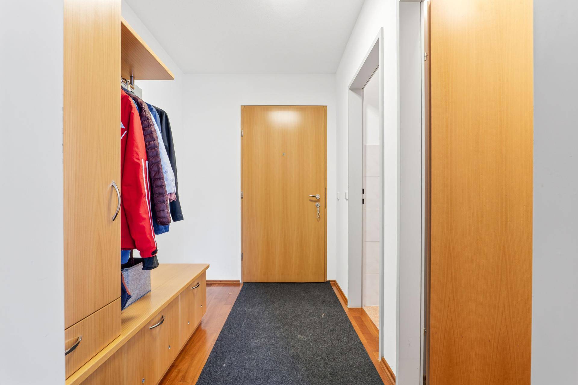 Eingangsbereich mit Garderobe, Schuhablage und Holzboden, praktisch gestaltet.