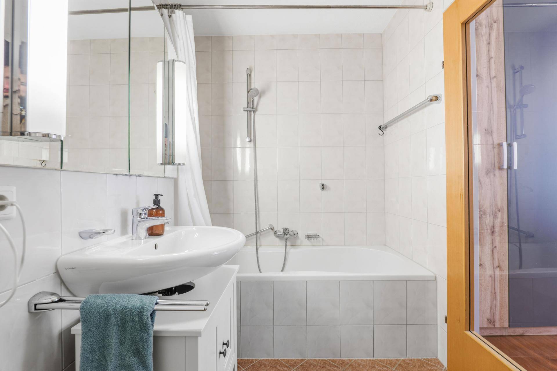 Badezimmer mit Badewanne, Duschfunktion und praktischen Haltegriffen für Sicherheit.