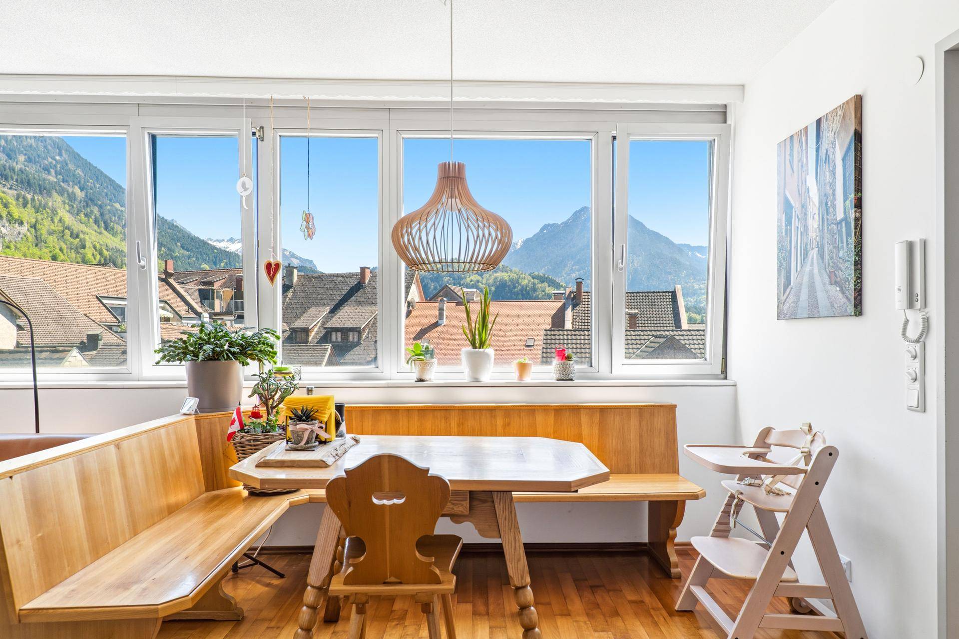 Heller Essbereich mit traditionellen Holzmöbeln und Panoramafenstern mit Bergblick.