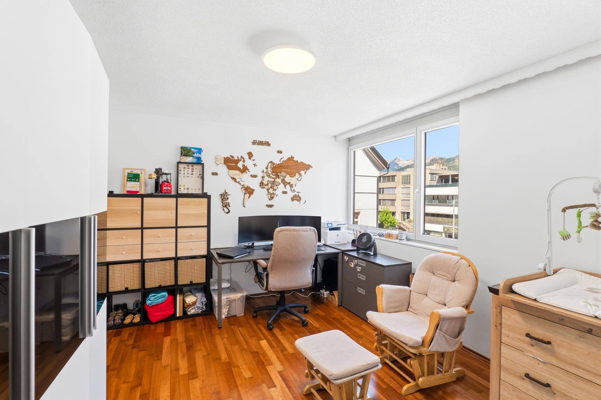 Helles Arbeitszimmer mit Stauraum, Holzboden und dekorativer Weltkarte an der Wand.