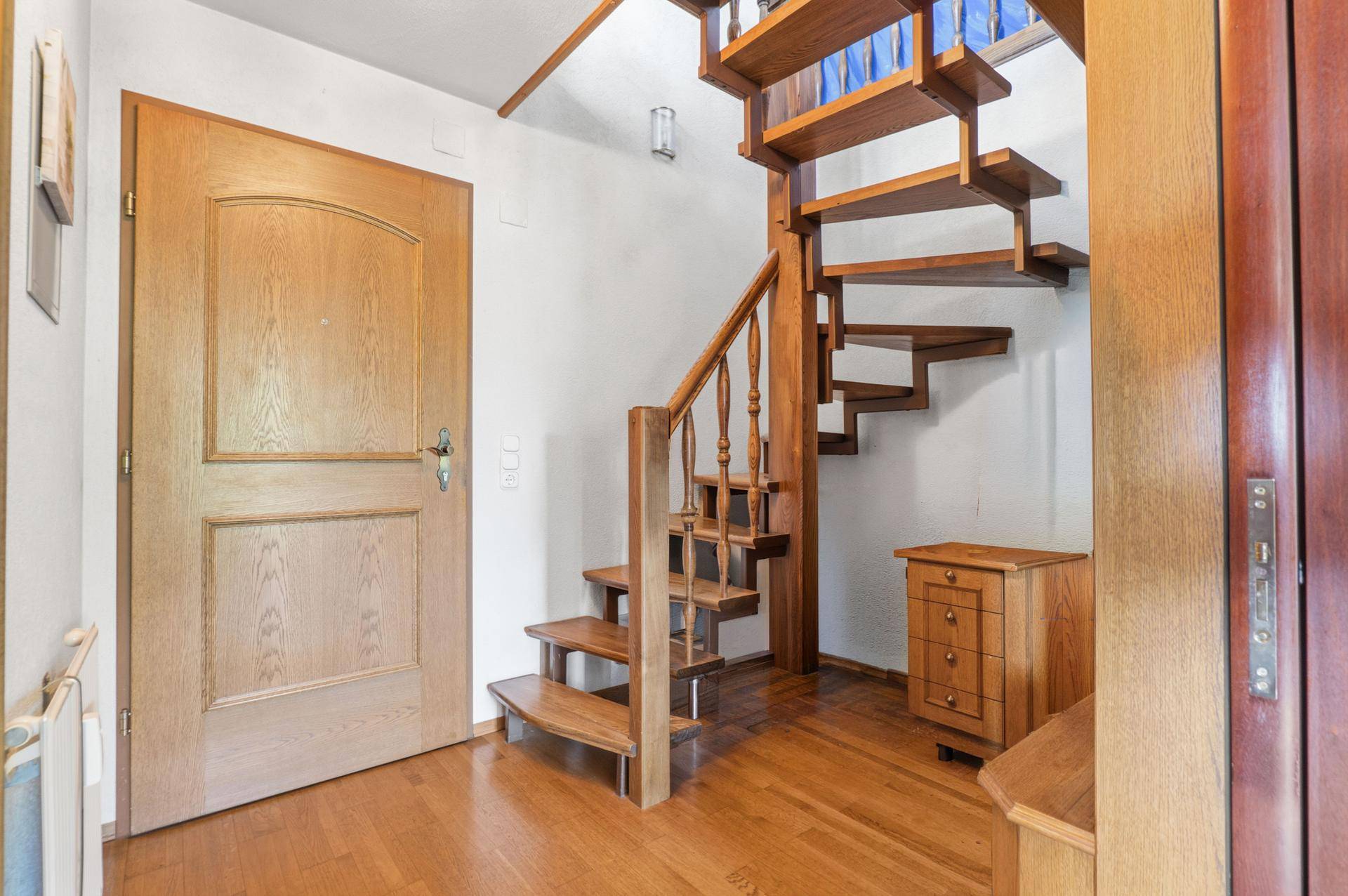 Eingangsbereich mit Holztreppe und massiver Holztür.
