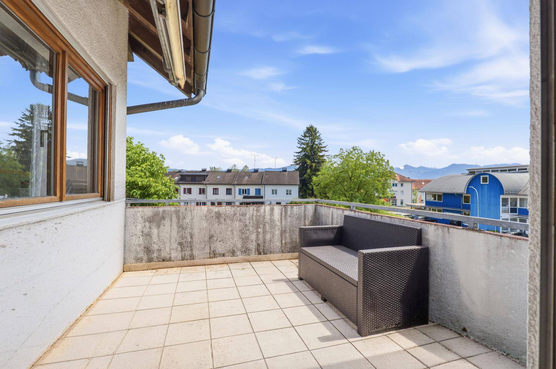 Balkon mit Fliesenboden, Sitzgelegenheit und weitem Blick über die Umgebung und Berge.