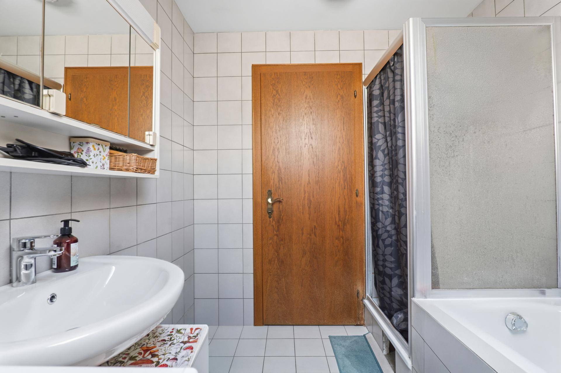 Badezimmer mit Waschbecken, Spiegelschrank und Duschkabine.