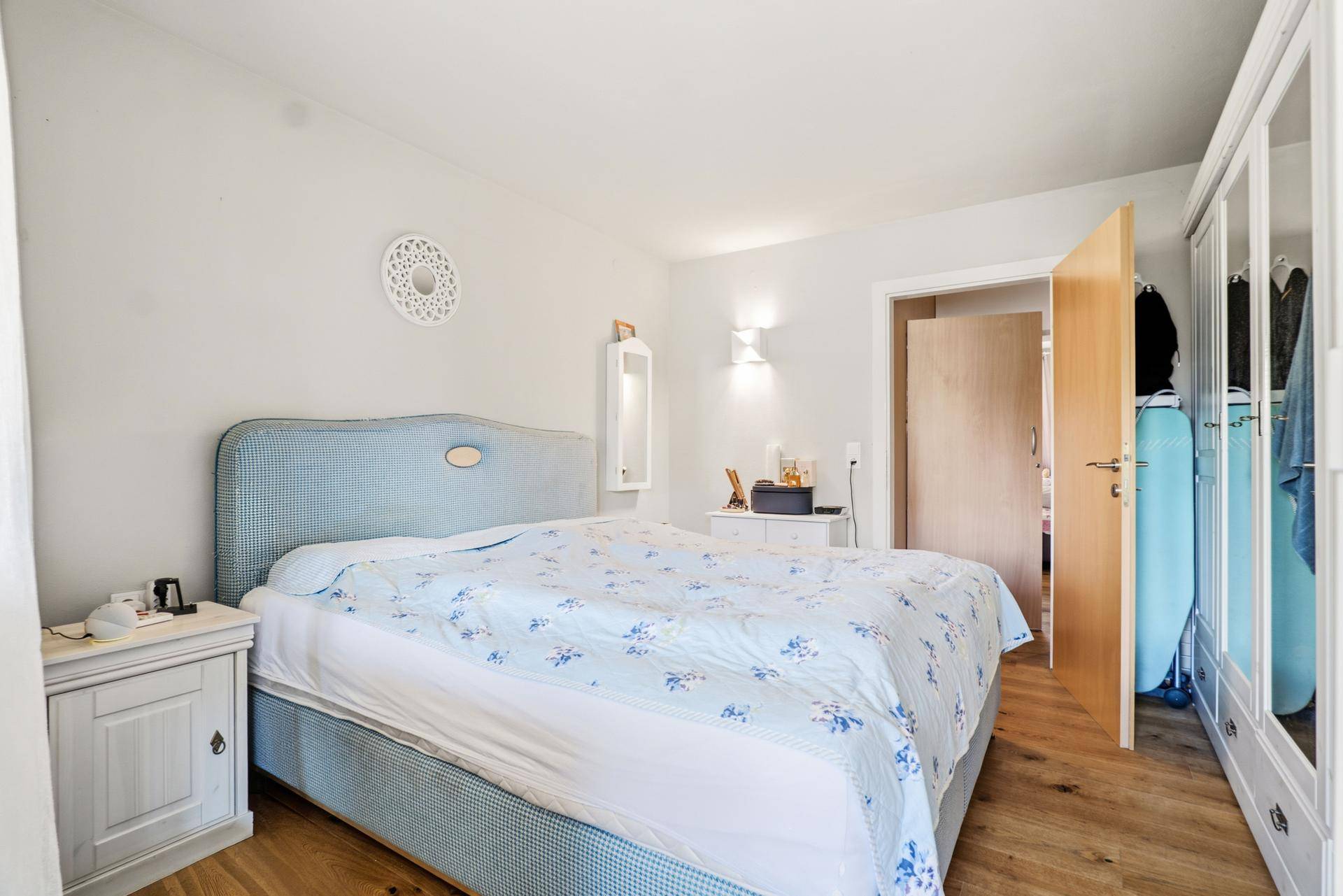 Schlafzimmer mit Doppelbett, Holzboden und weißem Kleiderschrank.